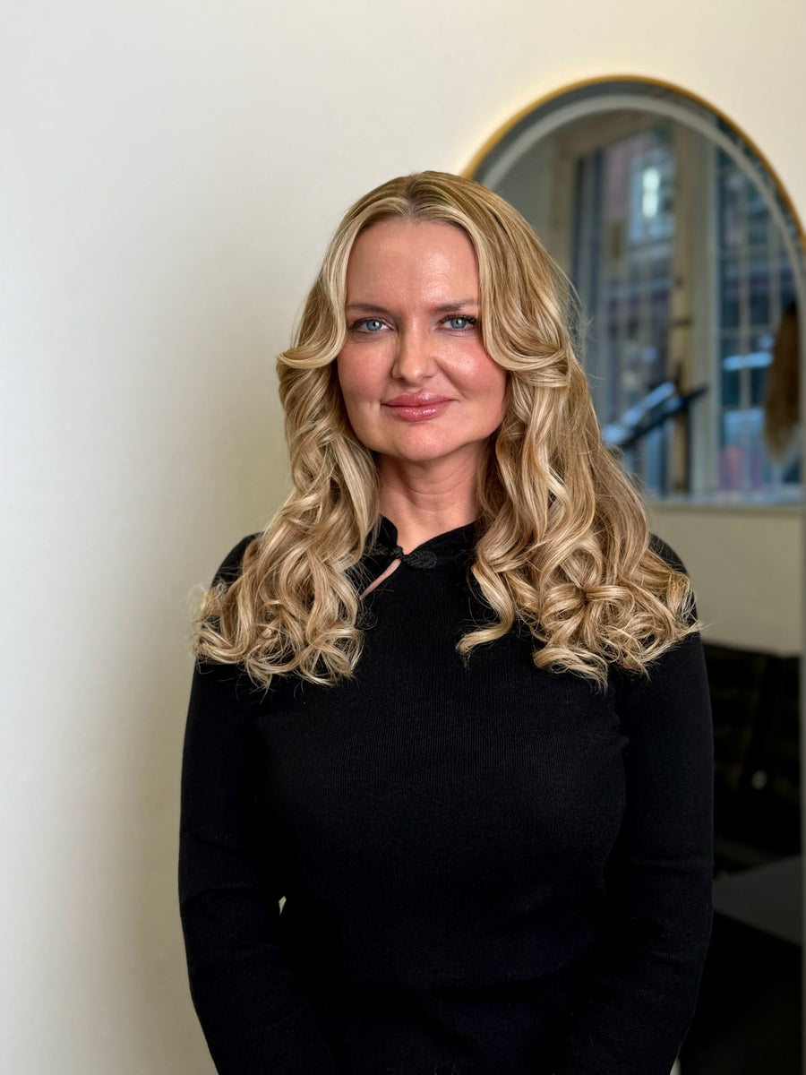 Kund med blont, lockigt hår efter färgning och sy in löshår i Fairwithhairs salong