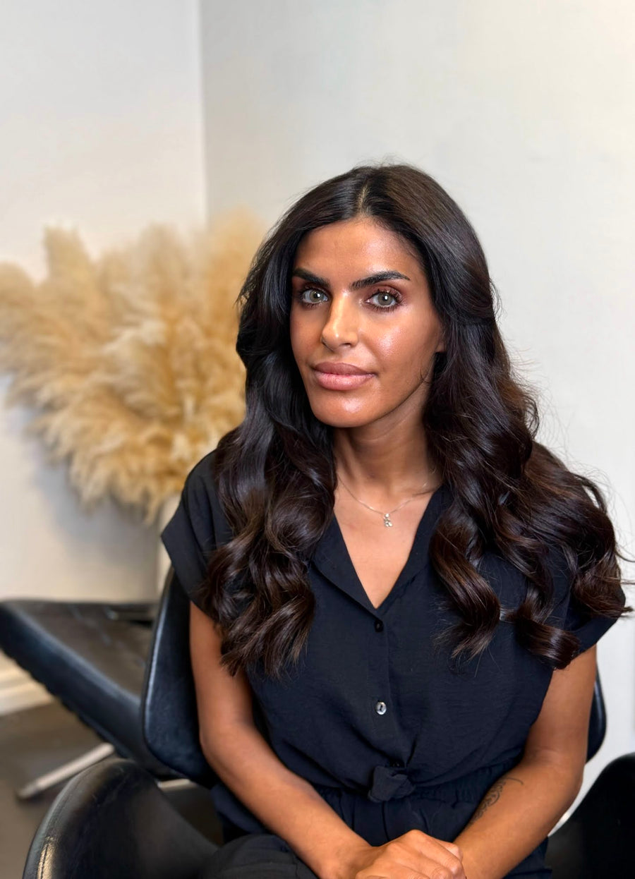 Kund med långt, mörkt och vågigt hår efter isättning av tejp löshår och styling i Fairwithhairs salong