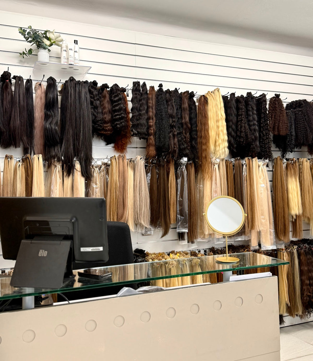 Receptionen i Fairwithhairs salong och hårbutik vid Odenplan i Stockholm, med väggen av hair weft i bakgrunden